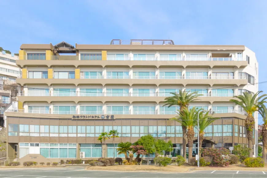 青空を背に建つ西浦グランドホテル吉慶の外観正面。