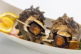 白い舟形の器に盛り付けられた、2つのさざえの壺焼き。