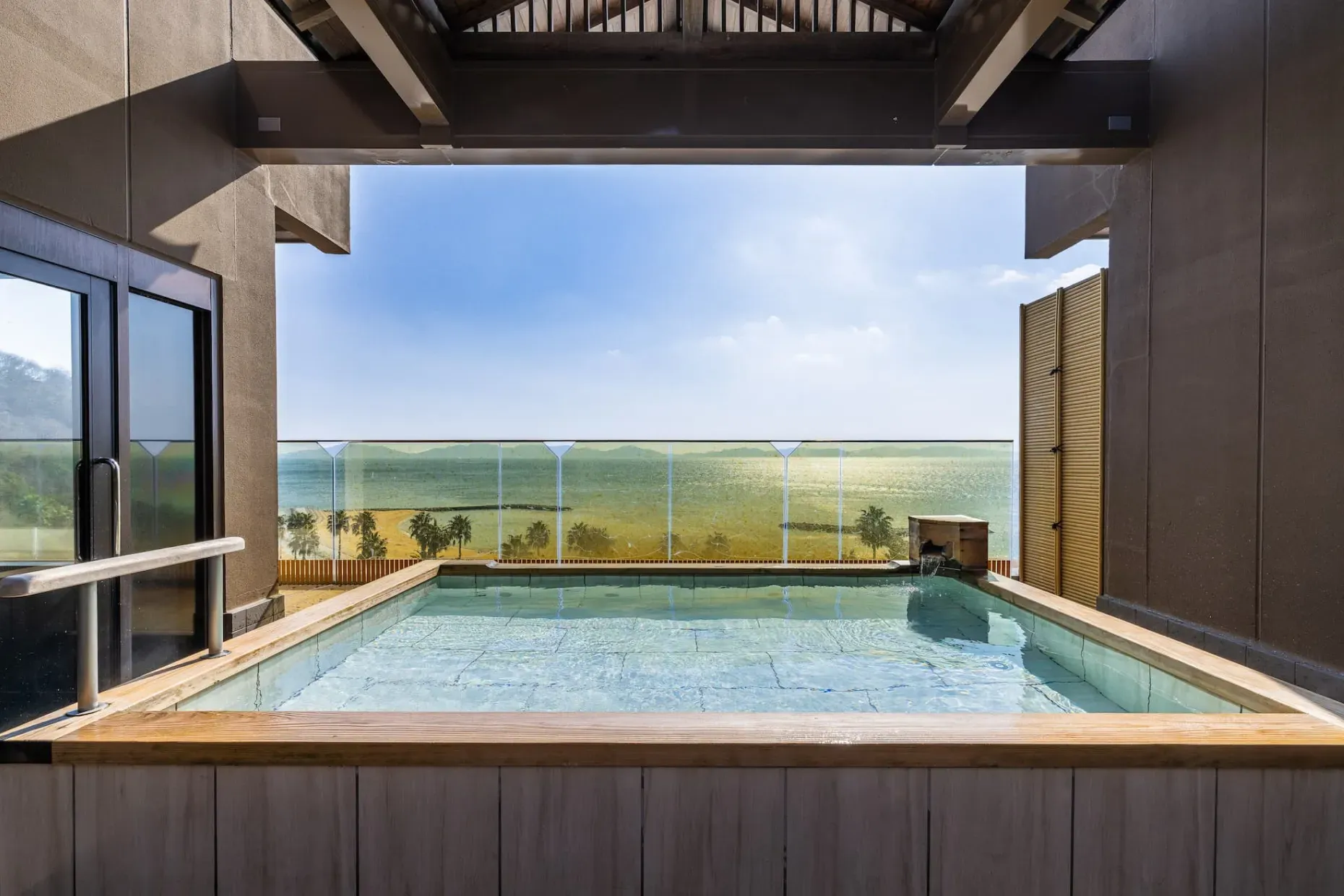 額縁のような柱の間から望む、陽光に煌めく三河湾と開放的な展望露天風呂「海こうこう」。
