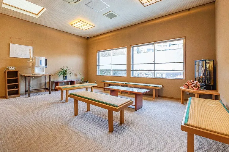 畳敷きの座面が心地よい長椅子が並ぶ、和モダンな休憩スペース。左奥にはウォーターサーバーがあり、広々とした明るい室内でゆったりと水分補給や休憩ができる空間です。